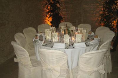Salle à manger rustique avec murs en pierre, table en bois, chaises assorties et porte-fenêtre donnant sur l'extérieur.