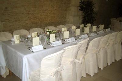 Salle à manger rustique avec murs en pierre, table en bois, chaises assorties et porte-fenêtre donnant sur l'extérieur.