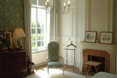 Salle à manger rustique avec murs en pierre, table en bois, chaises assorties et porte-fenêtre donnant sur l'extérieur.