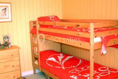 Salle à manger rustique avec murs en pierre, table en bois, chaises assorties et porte-fenêtre donnant sur l'extérieur.