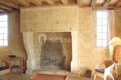 Salle à manger rustique avec murs en pierre, table en bois, chaises assorties et porte-fenêtre donnant sur l'extérieur.