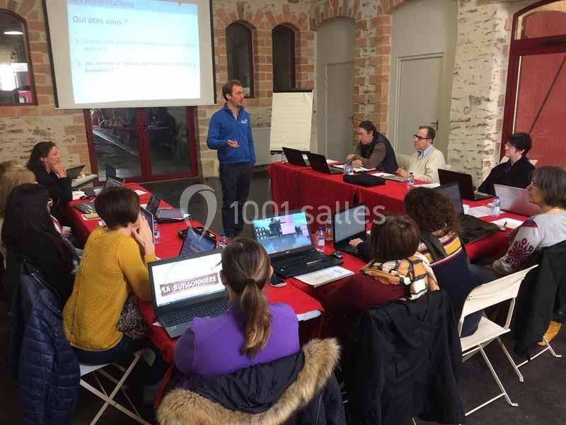 Un formateur s'adresse à un groupe de personnes assises autour d'une table avec des ordinateurs portables.