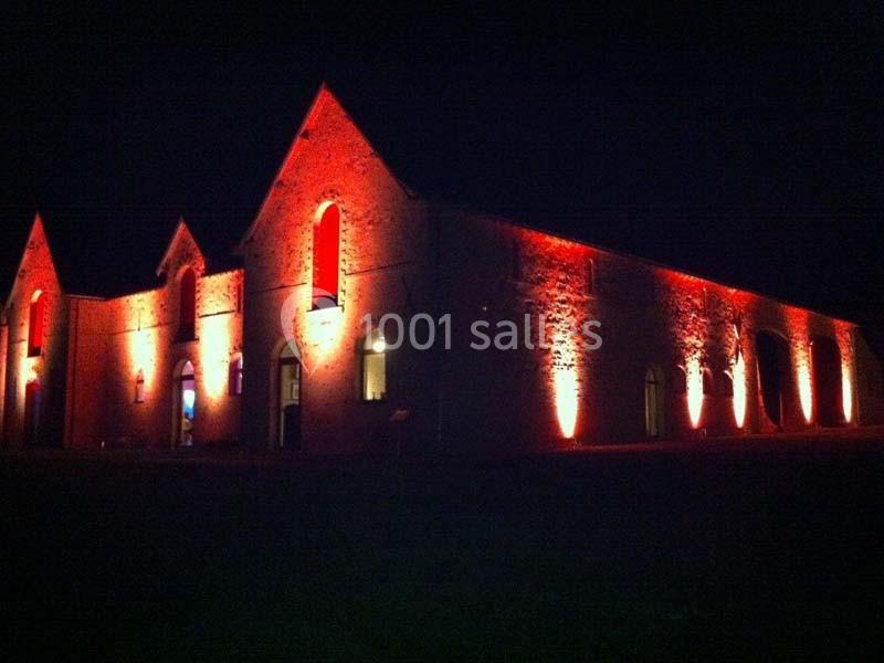 Bâtiment en briques éclairé par des lumières rouges, photographié de nuit.