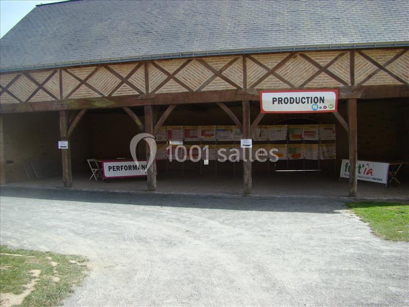 Abri en bois avec des panneaux d'information affichés à l'intérieur, entouré d'un sol en gravier et d'herbe.