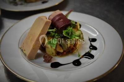 Filet de poisson servi sur un lit de légumes, garni de tomates séchées, herbes fraîches, et accompagné d'agrumes.