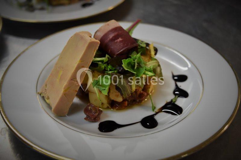 Assiette gastronomique avec foie gras, salade verte, viande roulée et décor de sauce balsamique.