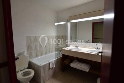 Filet de poisson servi sur un lit de légumes, garni de tomates séchées, herbes fraîches, et accompagné d'agrumes.