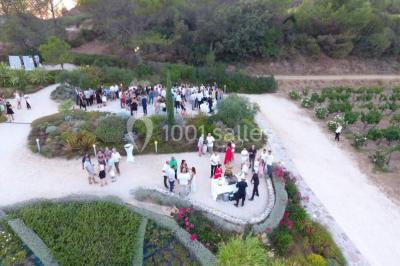 Vue d'un bâtiment moderne avec une structure blanche entouré de végétation méditerranéenne et d'un ciel bleu clair.