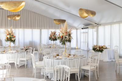 Vue d'un bâtiment moderne avec une structure blanche entouré de végétation méditerranéenne et d'un ciel bleu clair.