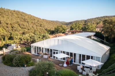 Vue d'un bâtiment moderne avec une structure blanche entouré de végétation méditerranéenne et d'un ciel bleu clair.