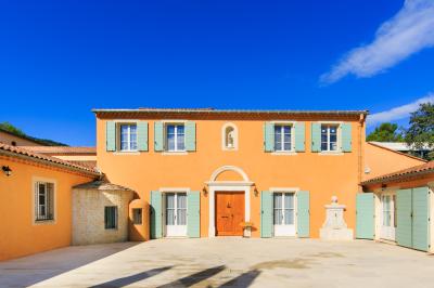 Vue d'un bâtiment moderne avec une structure blanche entouré de végétation méditerranéenne et d'un ciel bleu clair.