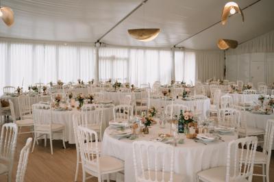 Vue d'un bâtiment moderne avec une structure blanche entouré de végétation méditerranéenne et d'un ciel bleu clair.