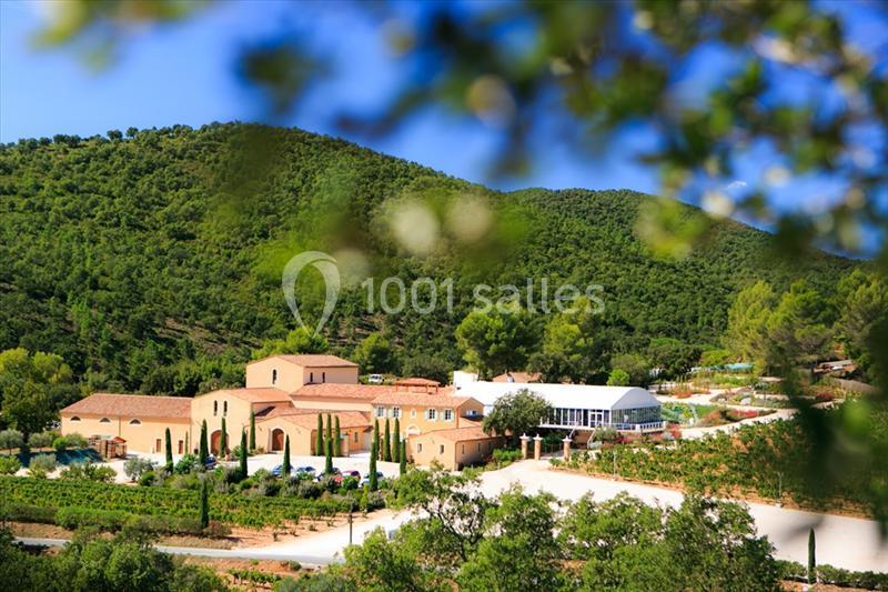 Domaine entouré de collines verdoyantes avec bâtiments en pierre et allées bordées de cyprès.