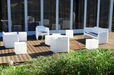 Vue d'un bâtiment moderne avec une structure blanche entouré de végétation méditerranéenne et d'un ciel bleu clair.