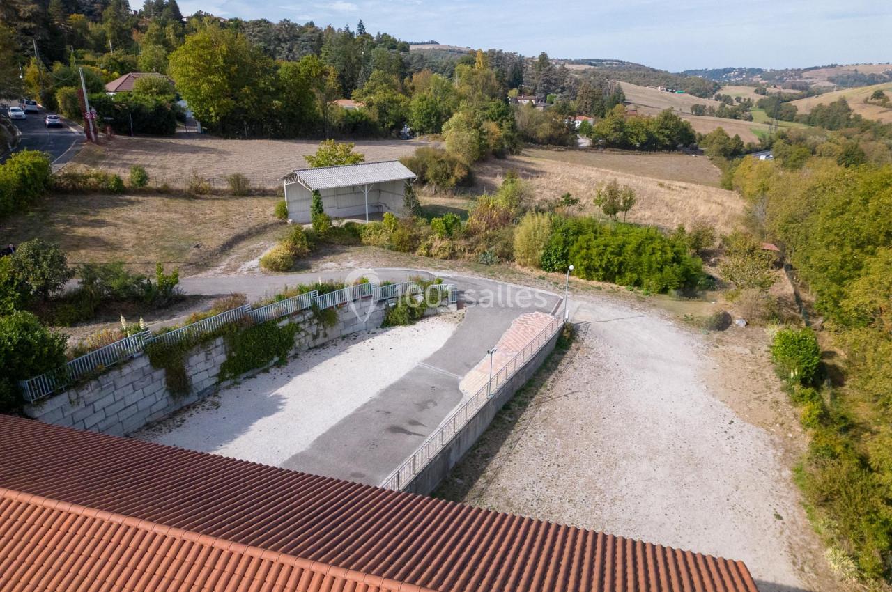 Vue aérienne d'un terrain avec un bâtiment en tôle, entouré de végétation et de routes de campagne.