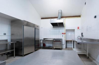Cuisine professionnelle avec équipements en inox, comprenant un réfrigérateur, une hotte, un four et des plans de travail.