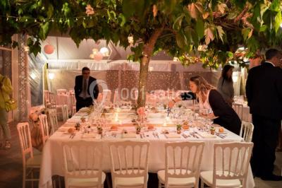 Groupe de personnes discutant sur une terrasse éclairée, entourée de végétation et de bougies.