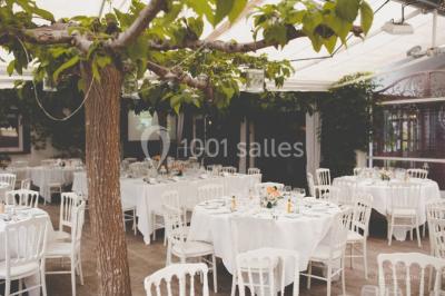 Groupe de personnes discutant sur une terrasse éclairée, entourée de végétation et de bougies.