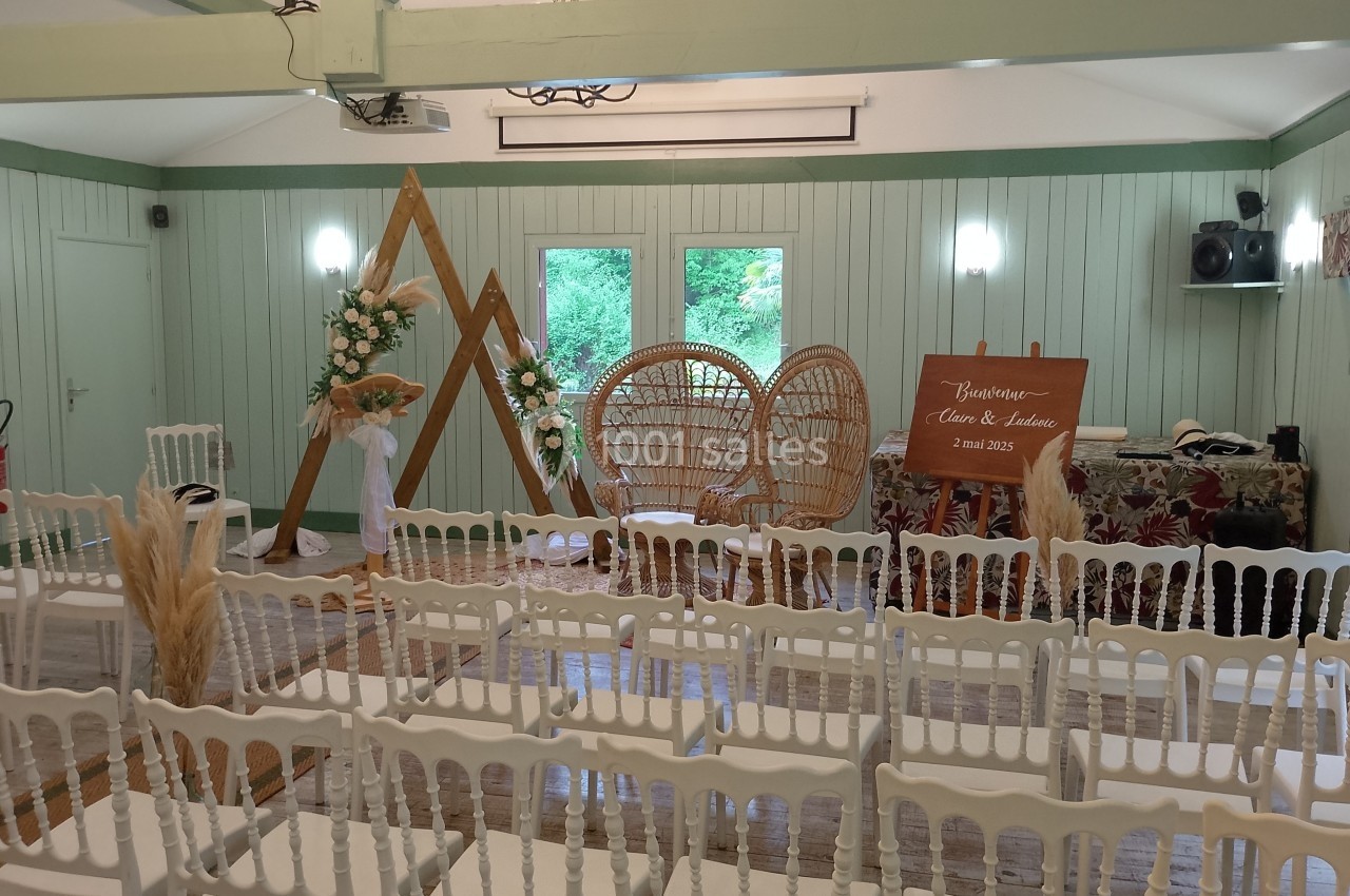 Salle décorée pour un mariage avec des chaises blanches, un panneau de bienvenue et des éléments floraux naturels.