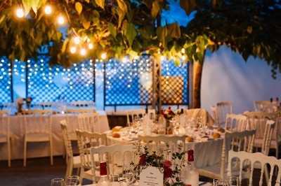 Groupe de personnes discutant sur une terrasse éclairée, entourée de végétation et de bougies.