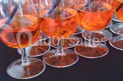 Verres de cocktail orange garnis de tranches d'orange et de pailles noires, disposés sur une nappe noire.