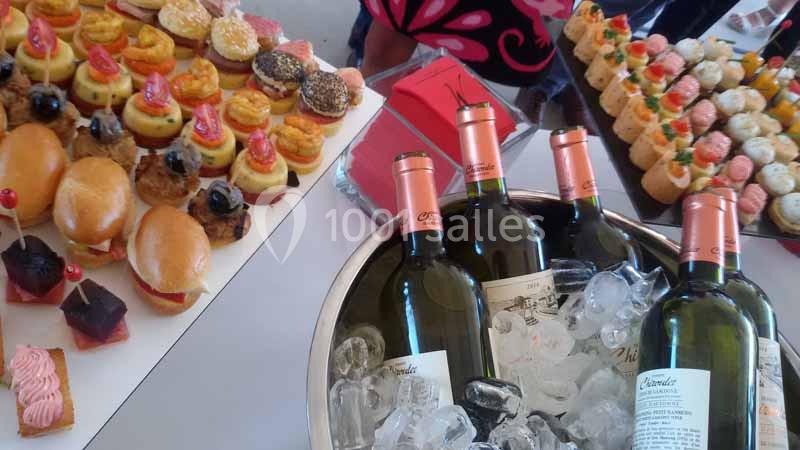 Plateau de bouchées sucrées et salées disposé à côté de bouteilles de vin blanc dans un seau rempli de glace.