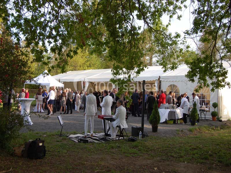 Groupe de personnes rassemblées près de tentes blanches dans un cadre extérieur, avec des musiciens en premier plan.