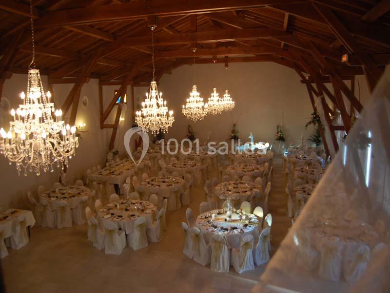 Salle de réception élégante avec tables rondes dressées et plusieurs lustres en cristal suspendus au plafond en bois.