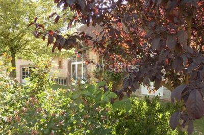 Salle de réception lumineuse avec tables rondes décorées, chaises blanches et poutres apparentes en bois.