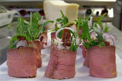 Jambon sur support, bol de tartare et croûtons disposés sur une table devant un mur en briques.