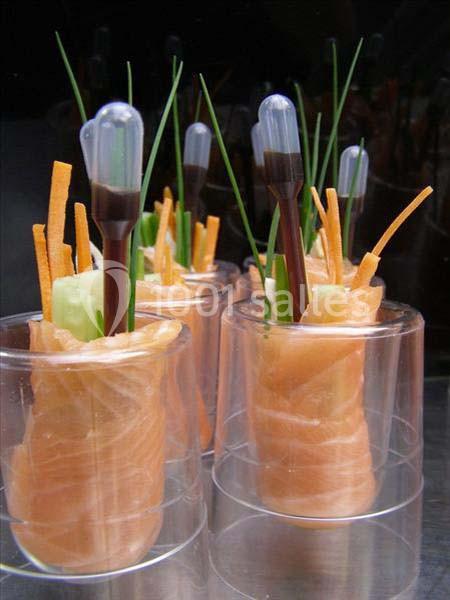 Rouleaux de saumon fumé garnis de légumes et accompagnés de pipettes contenant une sauce.