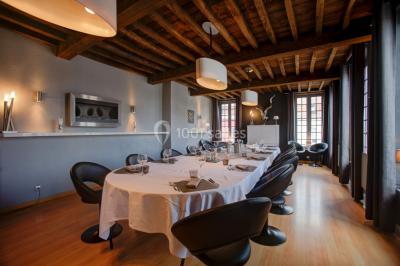 Jambon sur support, bol de tartare et croûtons disposés sur une table devant un mur en briques.