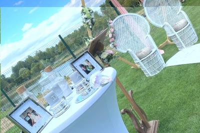 Table en bois décorée de bougies, fleurs et feuillage, entourée de chaises, sous une arche végétale dans une salle lumineuse.