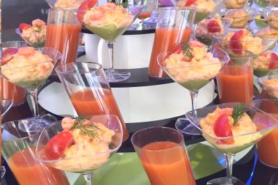 Table en bois décorée de bougies, fleurs et feuillage, entourée de chaises, sous une arche végétale dans une salle lumineuse.