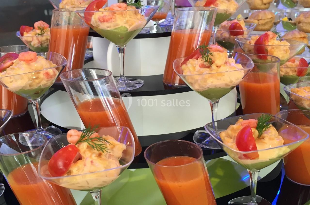 Buffet de verrines colorées avec gaspacho, crevettes, avocat et décorations de tomates et d'aneth.