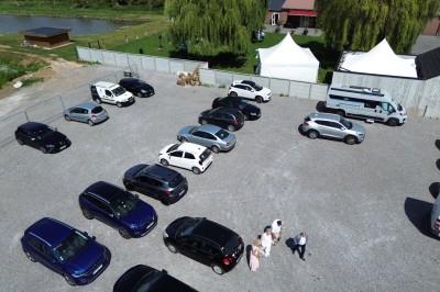 Tente blanche avec fenêtres en arc installée dans un jardin, entourée d'arbres et de pelouses sous un ciel dégagé.