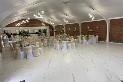 Tente blanche installée sur une pelouse verdoyante près d'un grand saule pleureur, sous un ciel bleu clair.