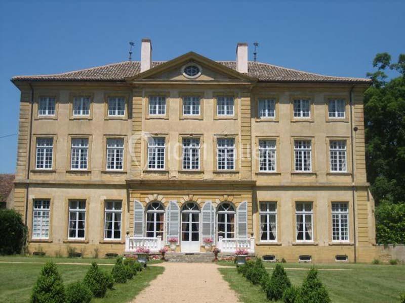 Façade d'un grand bâtiment ancien en pierre jaune avec des fenêtres symétriques et un jardin à l'avant.