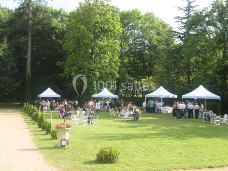 Des tentes blanches installées dans un parc verdoyant, entourées de personnes lors d'un événement en plein air.