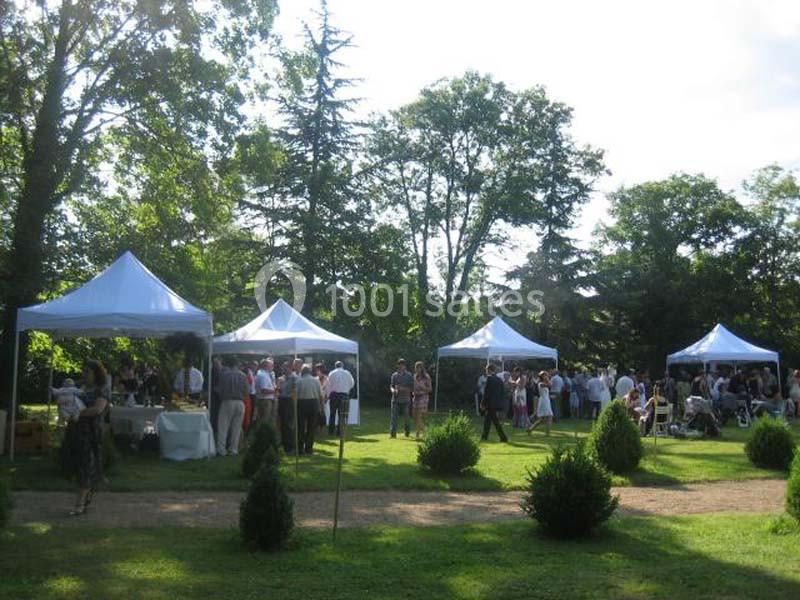 Des personnes rassemblées sous des tentes blanches dans un jardin verdoyant lors d'un événement en plein air.