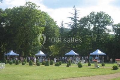 Chambre ancienne avec lit à baldaquin, fauteuil rouge, cheminée noire et murs tapissés de motifs verts.
