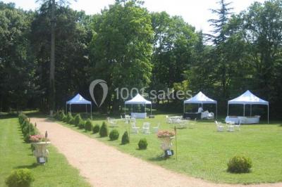 Chambre ancienne avec lit à baldaquin, fauteuil rouge, cheminée noire et murs tapissés de motifs verts.