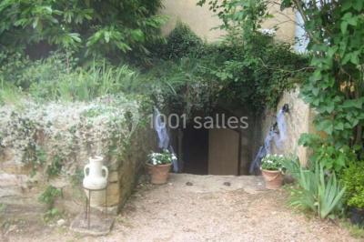 Chambre ancienne avec lit à baldaquin, fauteuil rouge, cheminée noire et murs tapissés de motifs verts.