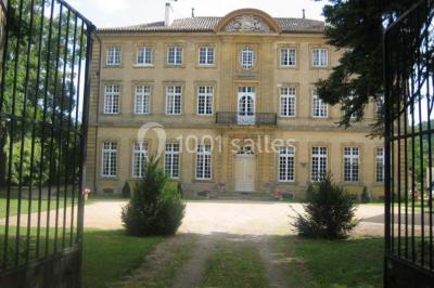 Chambre ancienne avec lit à baldaquin, fauteuil rouge, cheminée noire et murs tapissés de motifs verts.