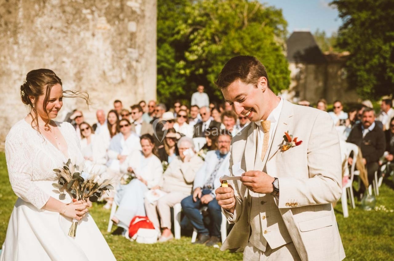 Un couple lors d'une cérémonie de mariage en extérieur, entouré d'invités assis sur des chaises.