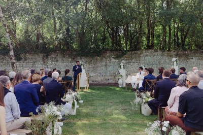 Bâtiment en pierre éclairé la nuit, avec un ciel bleu foncé en arrière-plan et un jardin sombre au premier plan.