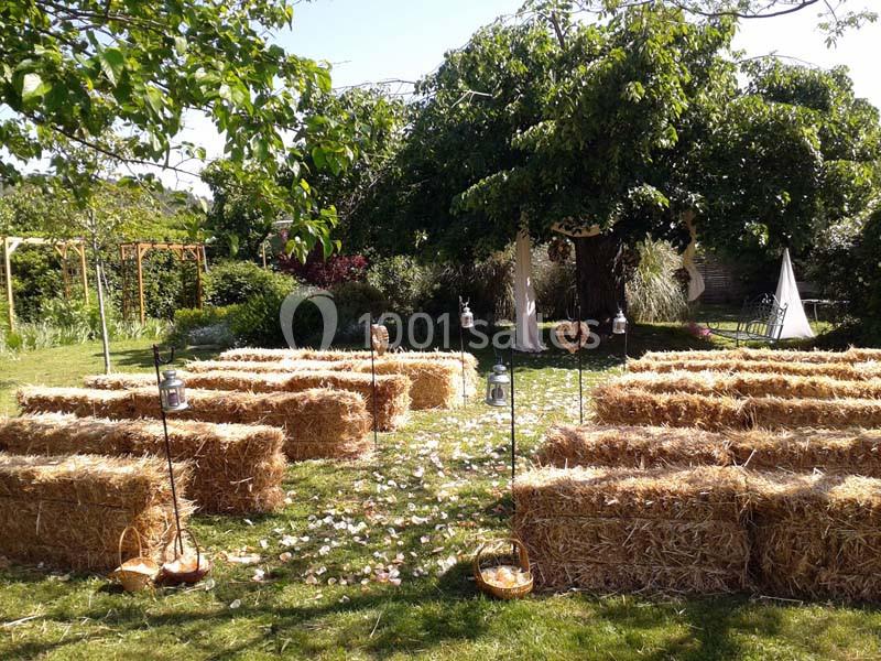 Disposition de bottes de paille en rangées pour une cérémonie en plein air, entourées de verdure et de décorations…