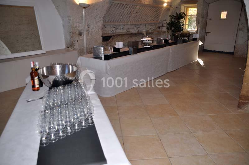 Table dressée avec des verres, un seau à glace et des bouteilles dans une salle en pierre avec un éclairage naturel.