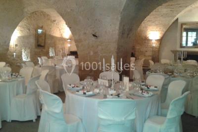Blason sculpté en pierre, usé par le temps, fixé sur un mur ancien avec des branches visibles au-dessus.