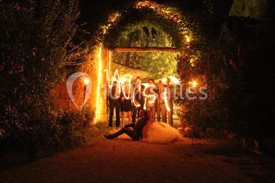 Un couple assis au sol devant un groupe de personnes tenant des lumières formant des lettres, sous une arche illuminée.